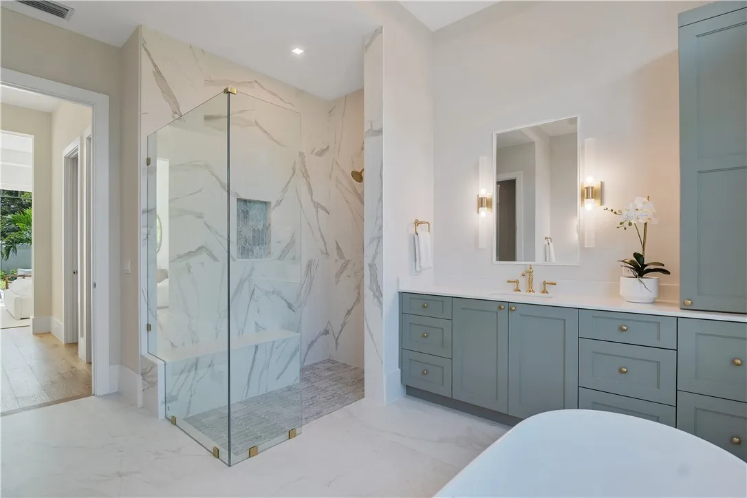 Custom stone shower with glass enclosure and sage vanity